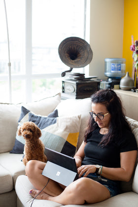 Person relaxing at home on a couch with their dog